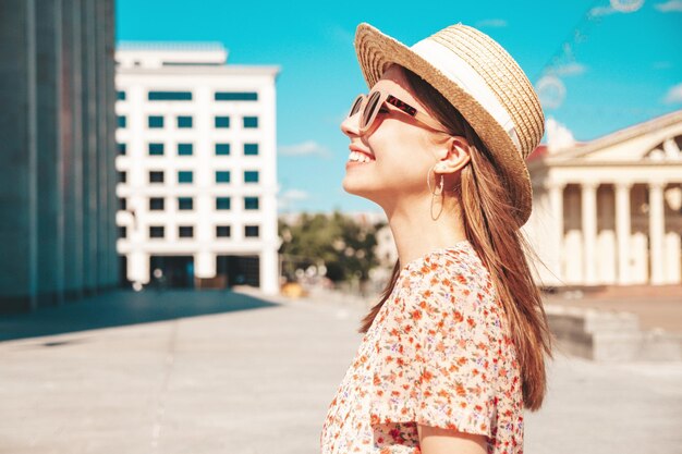 Jonge mooie lachende hipster vrouw in trendy zomerkleren Sexy zorgeloze vrouw die zich voordeed op de straat achtergrond bij zonsondergang Positief model buitenshuis vrolijk en gelukkig in zonnebril en hoed