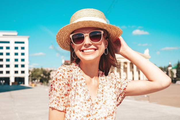 Jonge mooie lachende hipster vrouw in trendy zomerkleren Sexy zorgeloze vrouw die zich voordeed op de straat achtergrond bij zonsondergang Positief model buitenshuis vrolijk en gelukkig in zonnebril en hoed