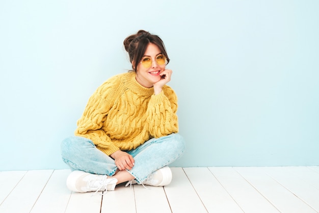 Jonge mooie lachende vrouw in trendy zomer gele hipster trui en jeans