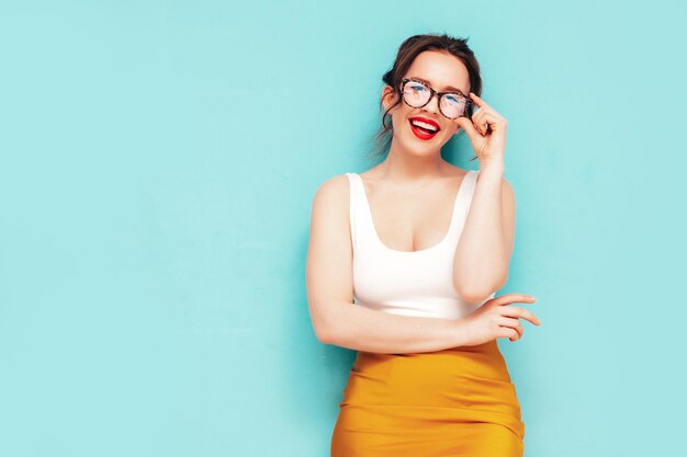 Jonge mooie lachende vrouw in trendy zomer gele rok kleding Sexy zorgeloze vrouw poseren in de buurt van muur in studio Positief model plezier vrolijk en gelukkig geïsoleerd In bril