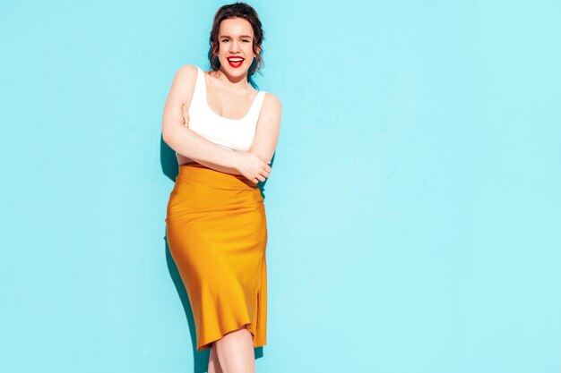 Jonge mooie lachende vrouw in trendy zomer gele rok kleding Sexy zorgeloze vrouw poseren in de buurt van muur in studio Positief model plezier vrolijk en gelukkig geïsoleerd