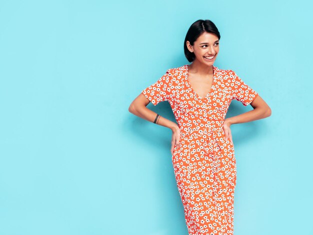 Jonge mooie lachende vrouw in trendy zomer rode jurk Sexy zorgeloze vrouw poseren in de buurt van blauwe muur in studio Positief model plezier vrolijk en gelukkig geïsoleerd