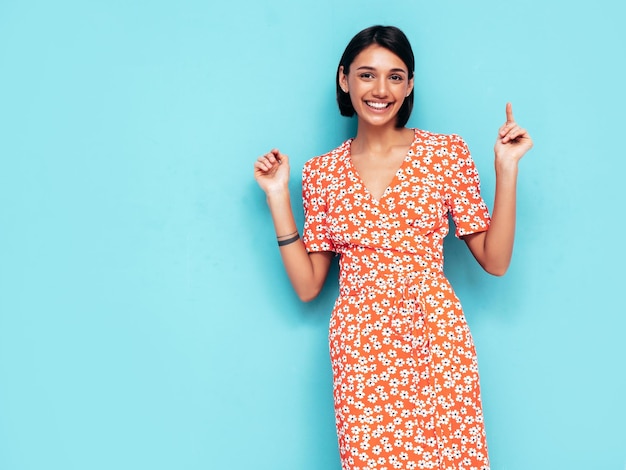 Jonge mooie lachende vrouw in trendy zomer rode jurk Sexy zorgeloze vrouw poseren in de buurt van blauwe muur in studio Positief model plezier vrolijk en gelukkig geïsoleerd