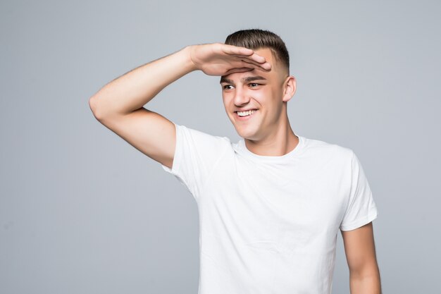 Jonge mooie man in een wit T-shirt geïsoleerd op wit kijkt uit