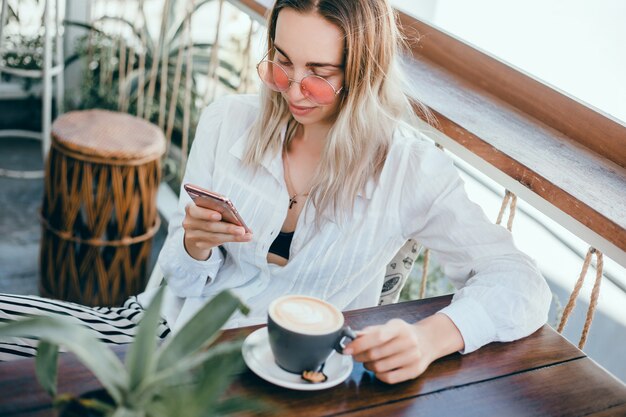 jonge mooie meid maakt gebruik van een smartphone op straat, surfen op het internet