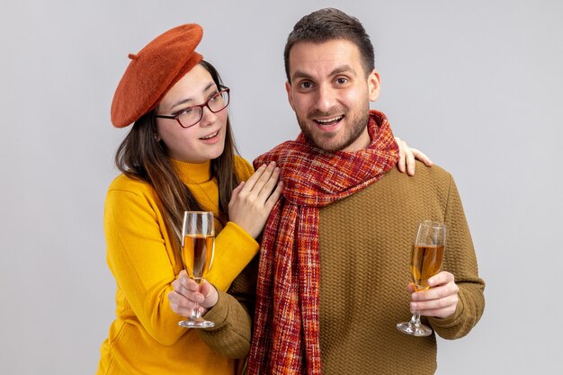 jonge mooie paar gelukkige man en glimlachende vrouw in baret met glazen champagne glimlachen vrolijk gelukkig verliefd samen vieren Valentijnsdag staande over witte muur