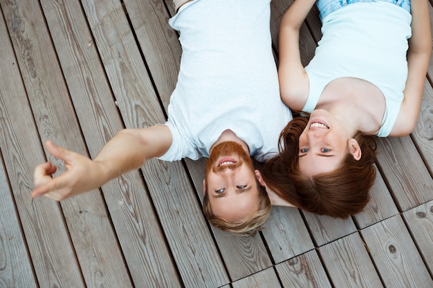 Jonge mooie paar glimlachen, liggend op houten planken