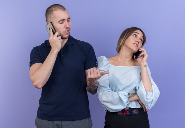 Jonge mooie paar man en vrouw die er zelfverzekerd uitzien terwijl ze op mobiele telefoons staan te praten