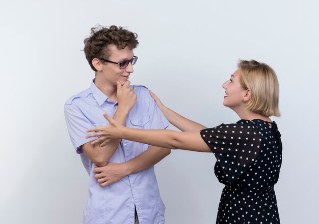 Jonge mooie paar man en vrouw gelukkig in liefde kijken elkaar over witte muur