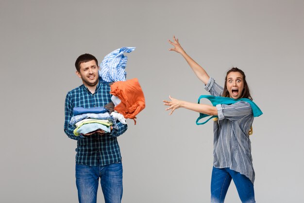 Jonge mooie paar wassen kleren houden, vechten over grijze muur