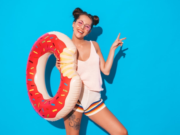 Jonge mooie sexy glimlachende hipster vrouw in zonnebril. met donut lilo opblaasbaar matras.