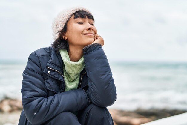 Jonge mooie spaanse vrouw die aan zee ademt