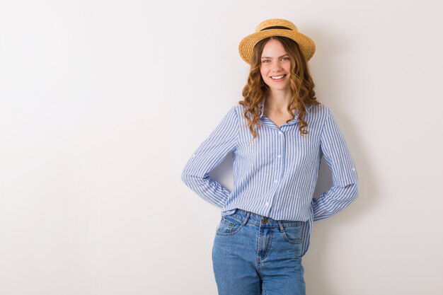 Jonge mooie stijlvolle vrouw in zomer stijl outfit poseren op witte muur stro hoed dragen