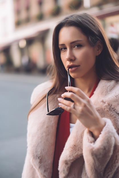 Jonge mooie stijlvolle vrouw lopen in roze jas