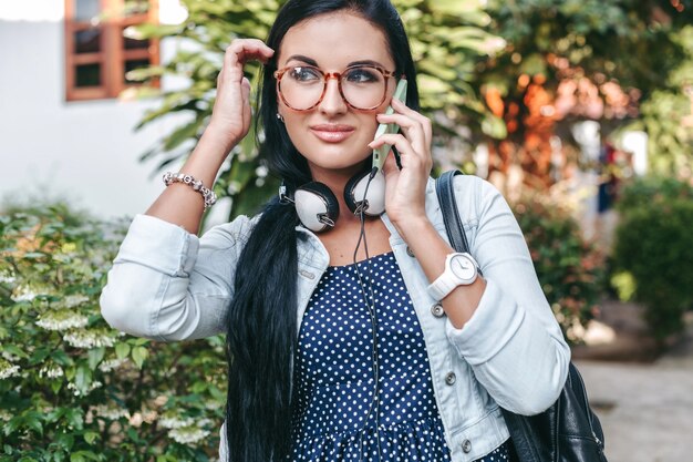 Jonge mooie stijlvolle vrouw praten over smartphone, rugzak, vintage denim stijl, glimlachen, gelukkig, zomer vaction houden