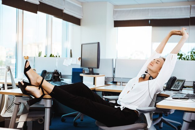 Jonge mooie succesvolle zakenvrouw rusten, ontspannen op de werkplek, op kantoor