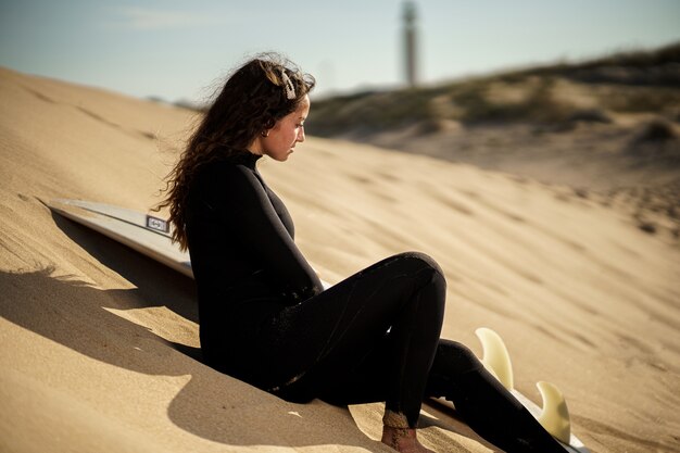 Jonge mooie surfer vrouw op het strand bij zonsondergang