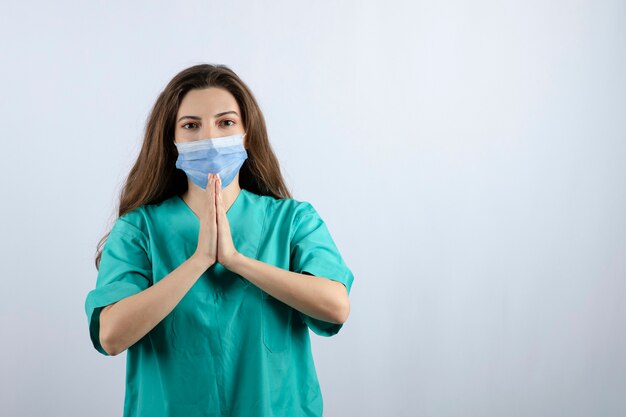 Jonge mooie verpleegster in groen uniform met een medisch masker