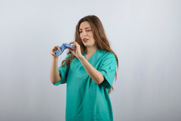 Jonge mooie verpleegster in groen uniform met een medisch masker