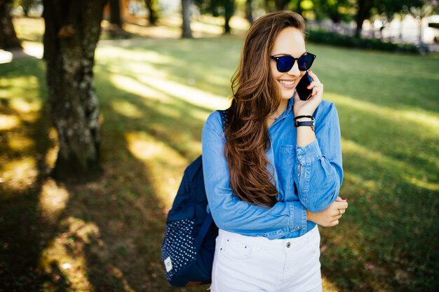 Jonge mooie vrouw buiten in park praten op mobiele telefoon