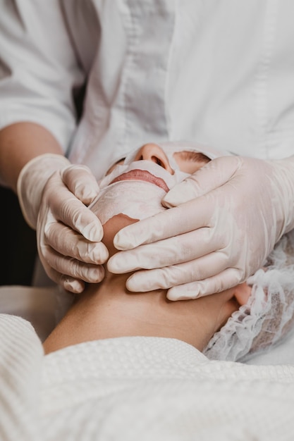 Jonge mooie vrouw die een behandeling van het huidmasker krijgt