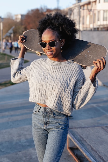 Gratis foto jonge mooie vrouw die een skateboard houdt