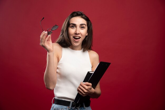 Jonge mooie vrouw die met glazen notitieboekjes houdt