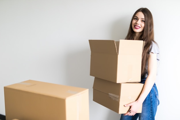 Jonge mooie vrouw die naar een nieuw appartement verhuist met kartonnen dozen met spullen