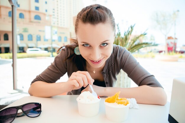 Jonge mooie vrouw die roomijs eet