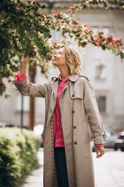 Jonge mooie vrouw die zich door de bloemen in park bevindt