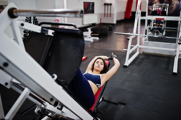 Jonge mooie vrouw doet oefeningen en werkt hard in de sportschool en geniet van haar trainingsproces