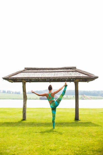 Jonge mooie vrouw doet yoga in ochtendpark in de buurt van meer