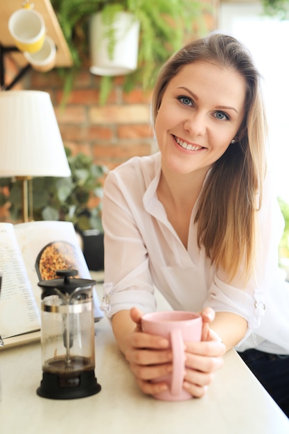 Jonge mooie vrouw, drinken koffie of thee