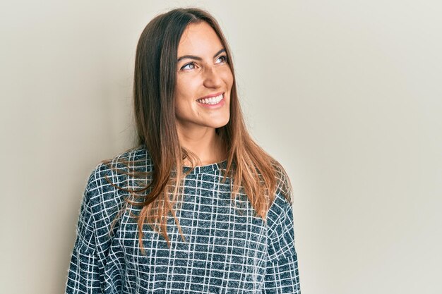 Jonge, mooie vrouw, gekleed in vrijetijdskleding die naar de zijkant kijkt, ontspannen profiel pose met een natuurlijk gezicht en een zelfverzekerde glimlach