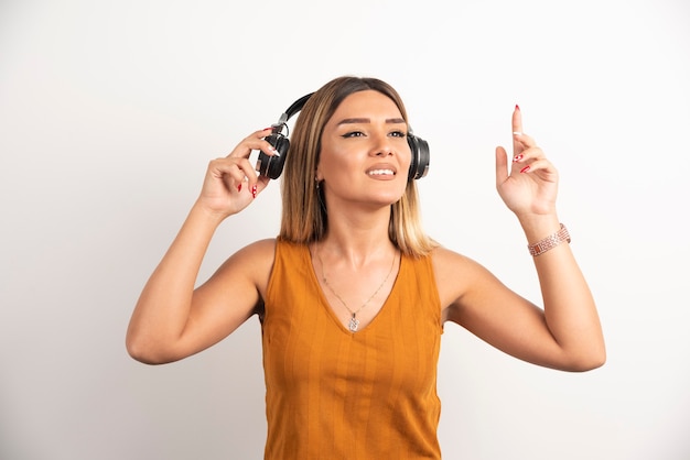 Jonge mooie vrouw hoofdtelefoon dragen op witte achtergrond.