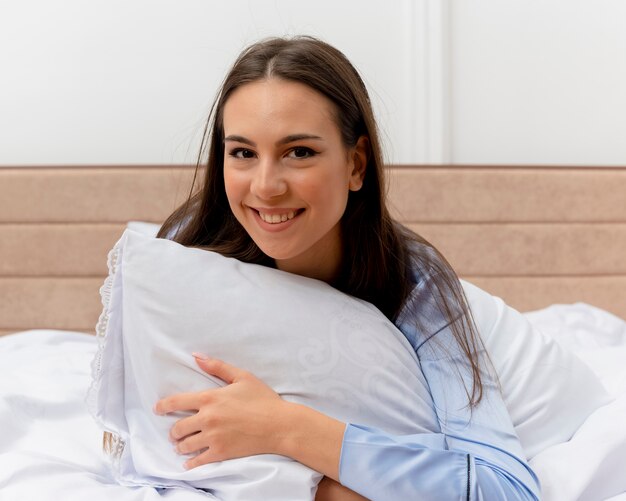 Jonge mooie vrouw in blauwe pyjama's tot op bed