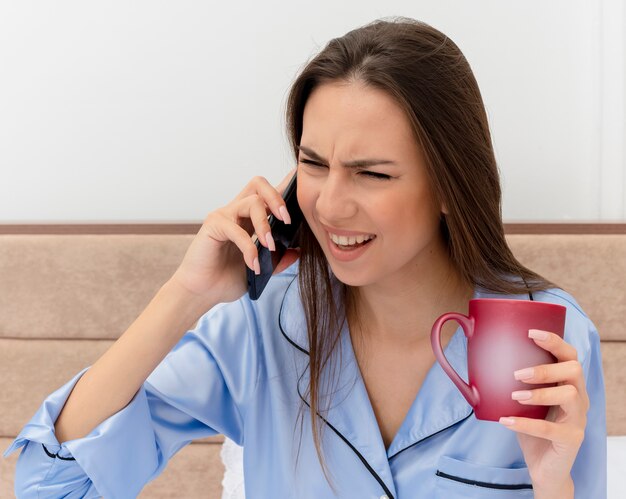 Jonge mooie vrouw in blauwe pyjama's tot op bed