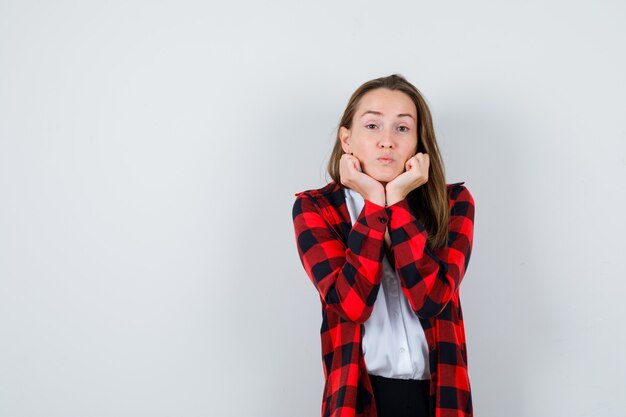 Jonge mooie vrouw in casual outfit kussen gezicht op haar handen en op zoek naar ongezellig, vooraanzicht.