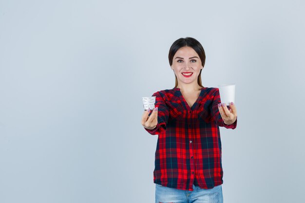 Jonge mooie vrouw in casual shirt, jeans poseren met plastic bril en er vrolijk uitzien, vooraanzicht.