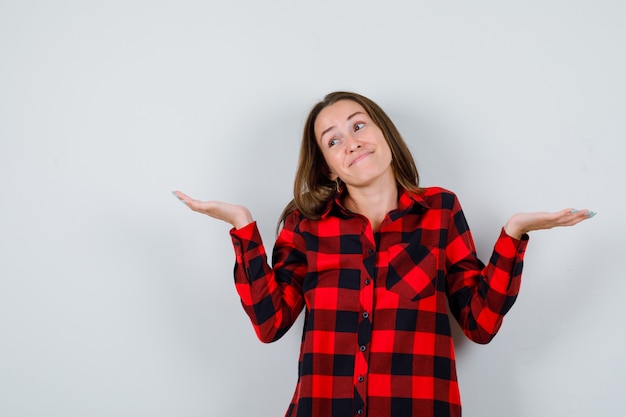 Jonge mooie vrouw in casual shirt met hulpeloos gebaar en vrolijk, vooraanzicht.