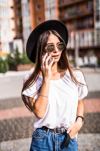 Jonge mooie vrouw in de telefoon van de zwarte hoedenbespreking op de de zomerstraat