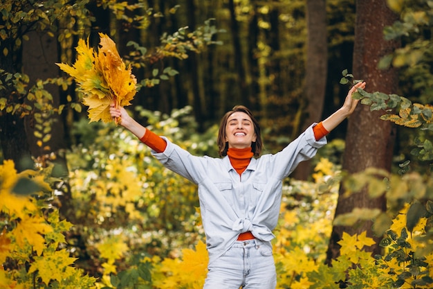 Jonge mooie vrouw in een herfst park vol met bladeren