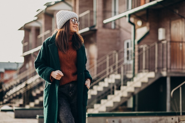 Jonge mooie vrouw in warme jas bij het huis