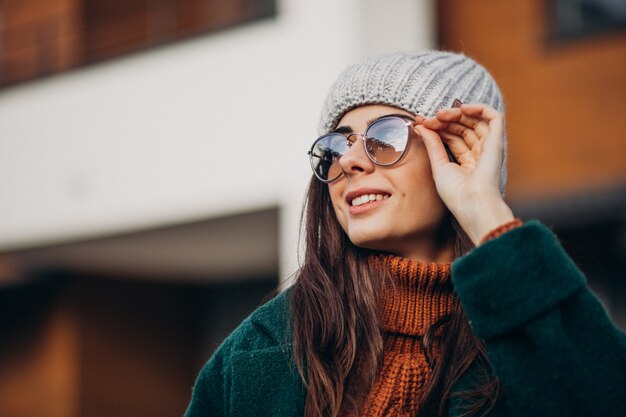 Jonge mooie vrouw in warme jas bij het huis