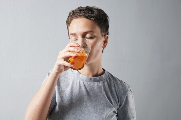 Jonge mooie vrouw met een gezonde perfecte huid die droomachtig haar verse organische wortelsinaasappelsap drinkt