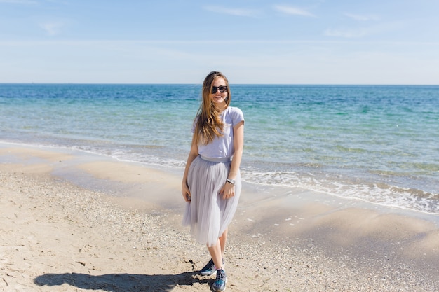 Jonge mooie vrouw met lang haar blijft in de buurt van blauwe zee