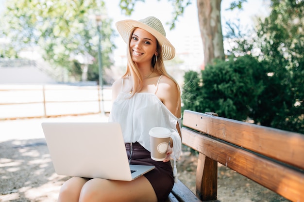 Jonge mooie vrouw met laptop op een parkbank