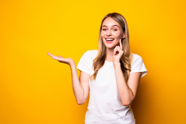 Jonge mooie vrouw met open palm die op gele muur wordt geïsoleerd