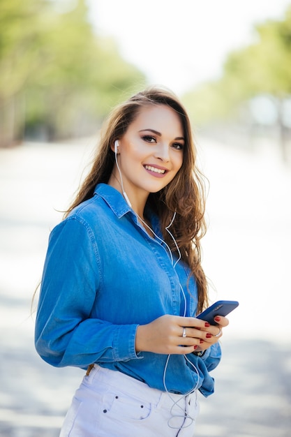 Jonge mooie vrouw met smartphone buiten in de straat. levensstijl portret