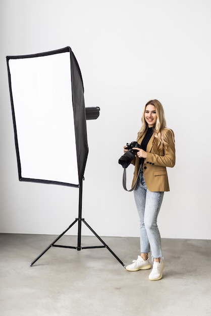 Gratis foto jonge mooie vrouw poseren voor een fotoshoot in een studio die een fotograaf fotografeert met een digitale camera
